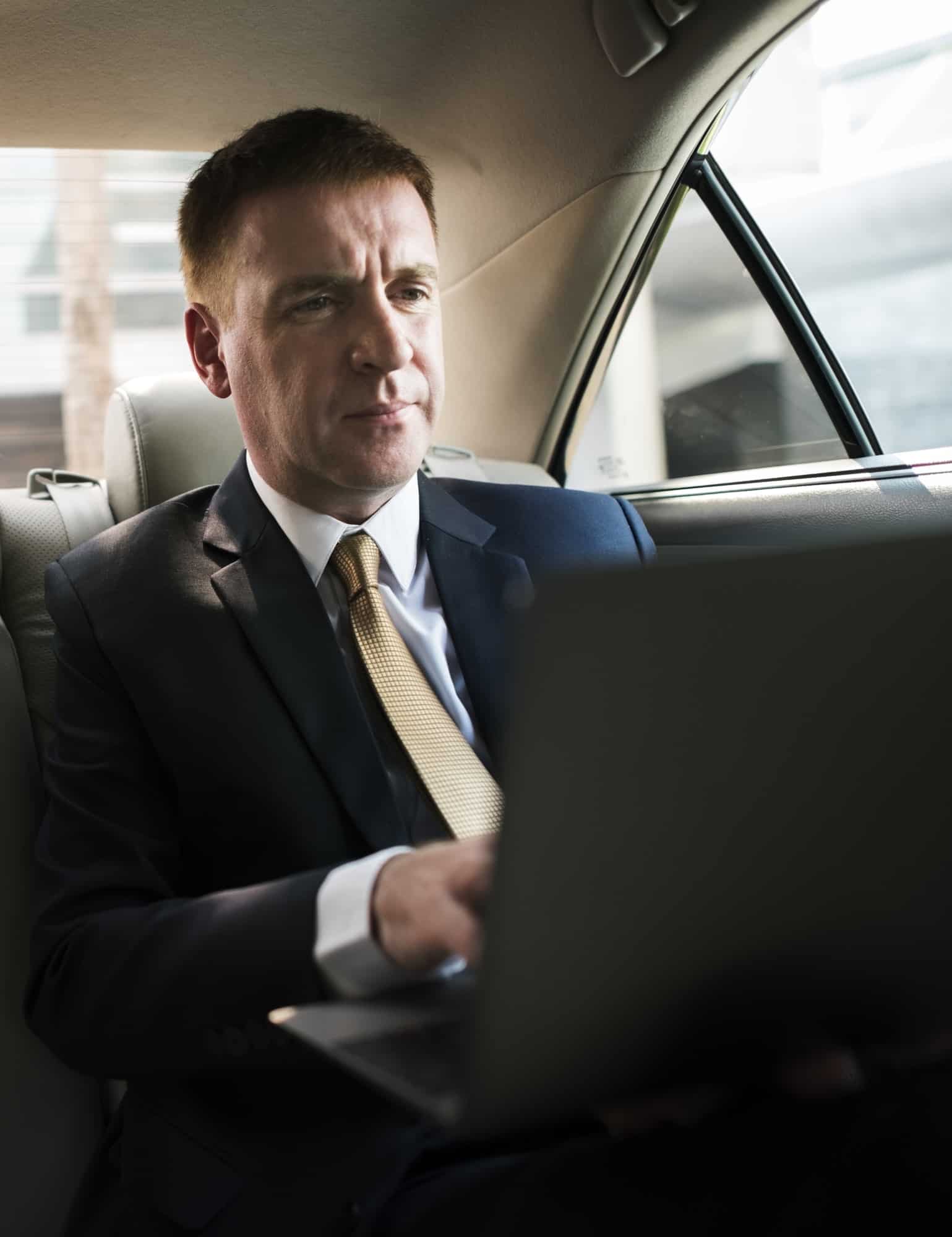 businessman inside a car working on his laptop Limousine Dubai